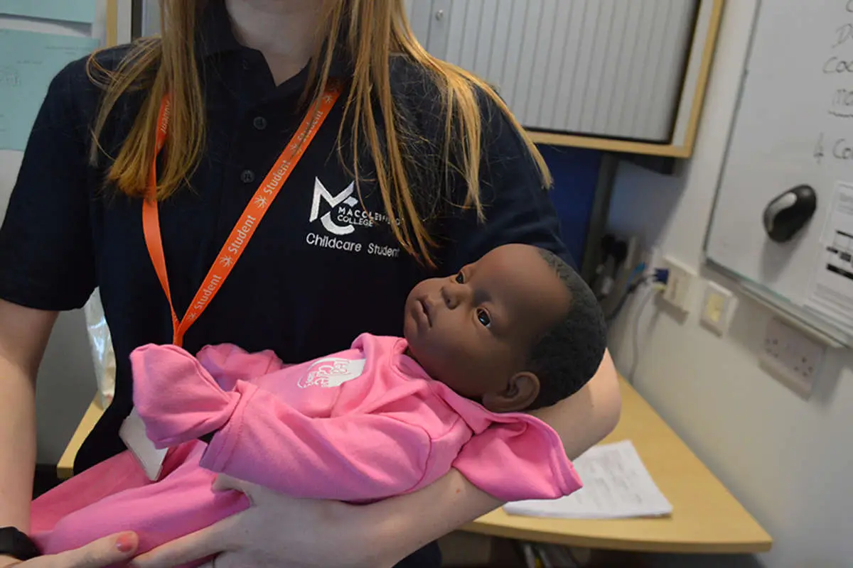 A childcare student holding a doll