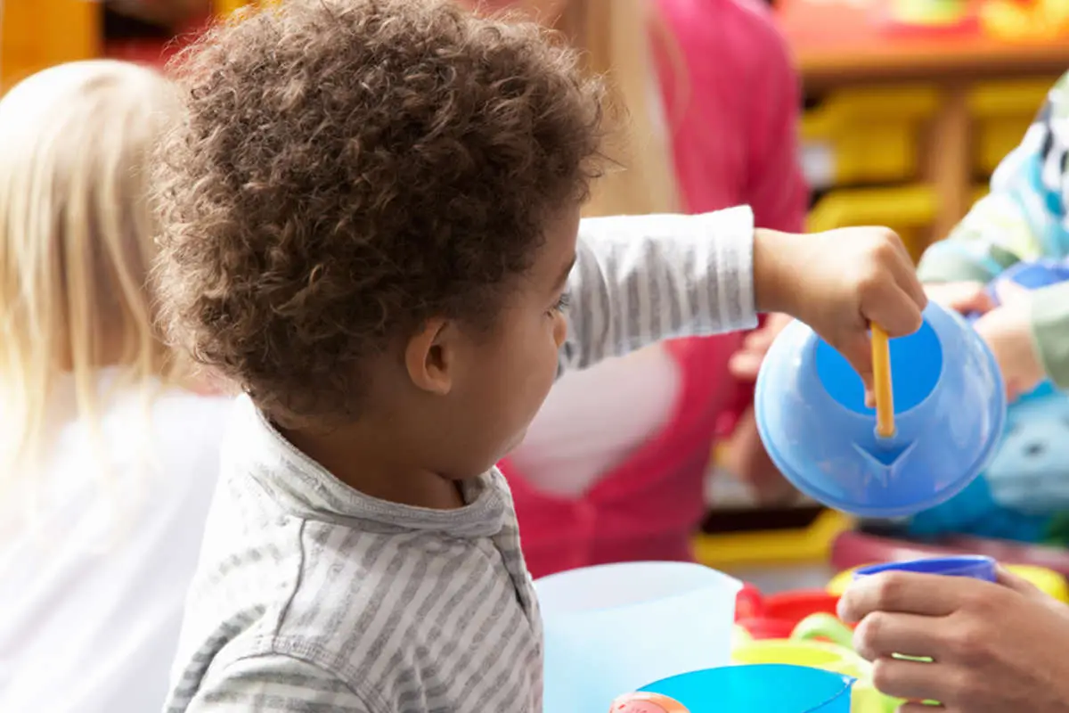 A child playing with a blue plastic teapot