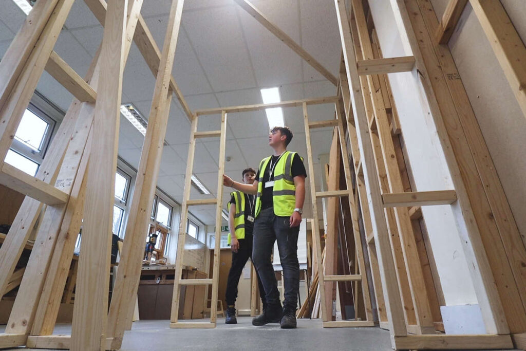 2 students inspect a large wooden frame