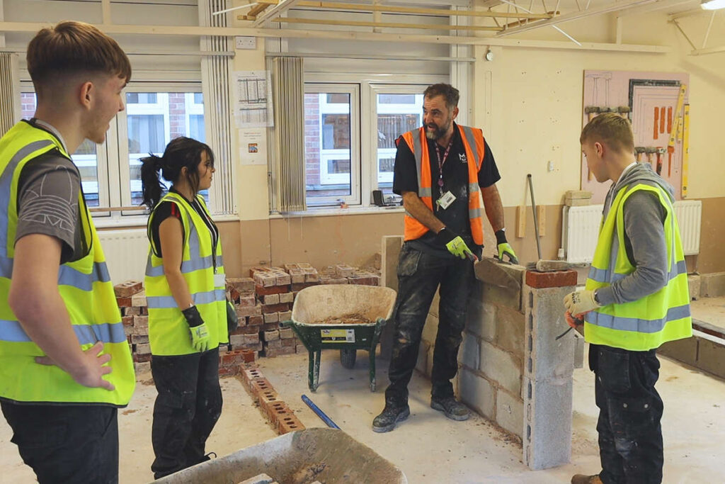 a demonstration in bricklaying is being given to 3 students