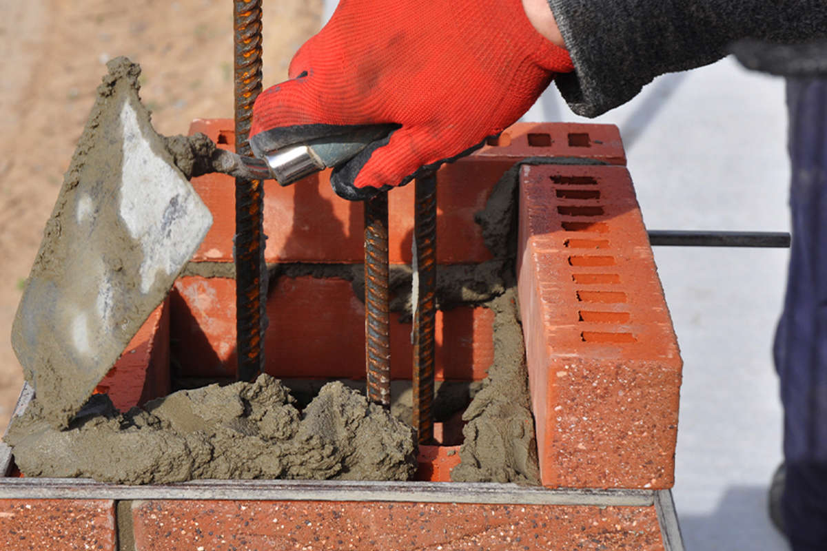 Mortar being placed on to bricks with a trowel