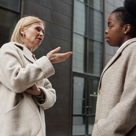 Two woman stood outside in coats have a conversation