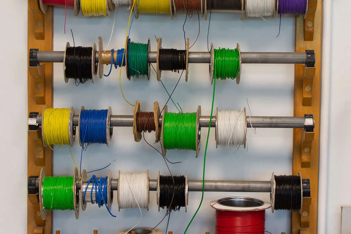 a shelving unit containing wires and cables in different colours of black, white, green, blue, yellow, red and purple