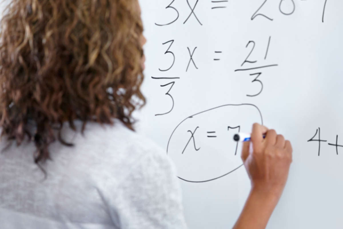 A woman working out a maths question on a whiteboard