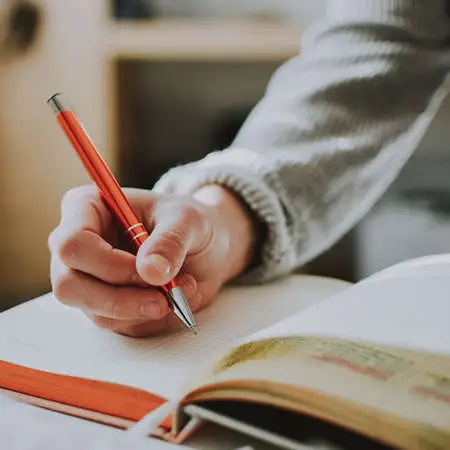 The close up of a person writing in a notebook