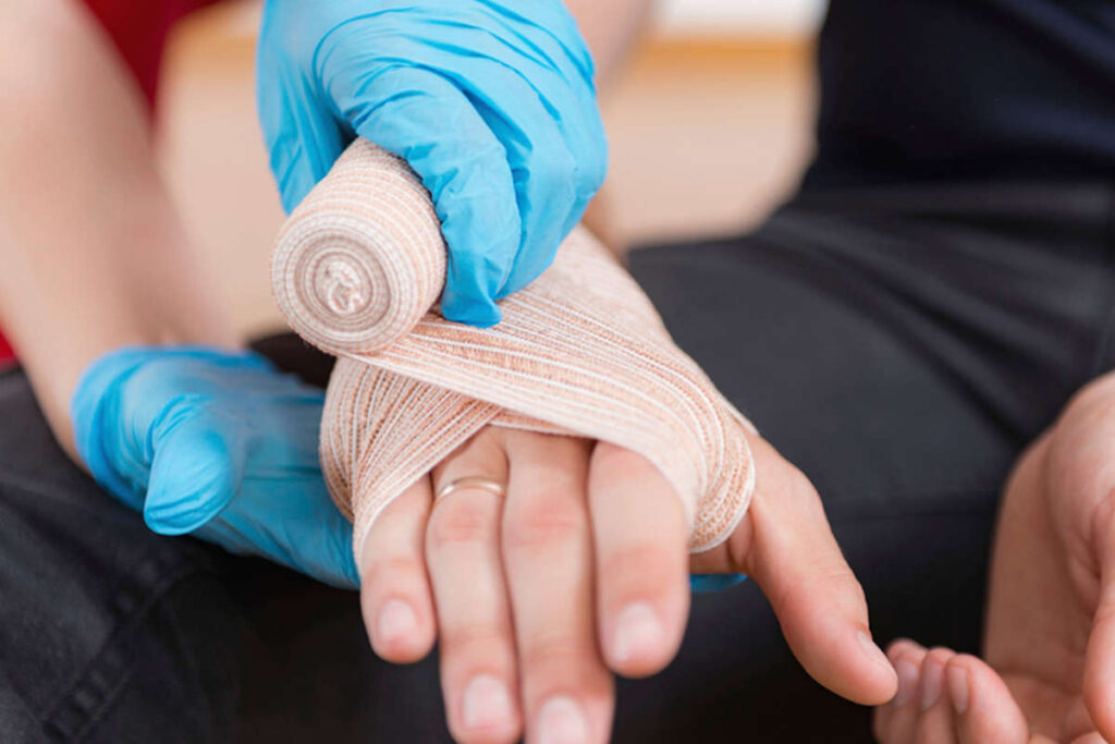 A close up of a mans hand being bandaged after an injury