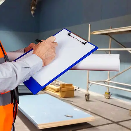 A man in a hi-viz jacket writing on a noteboard