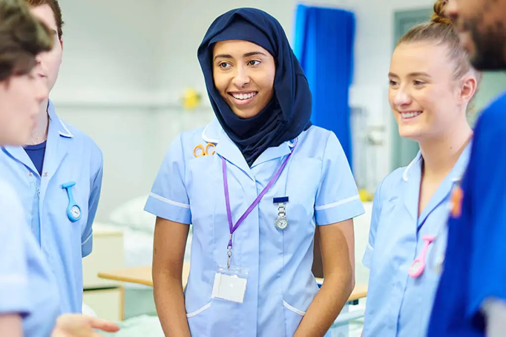 Group of student nurses stood talking in a hospital setting