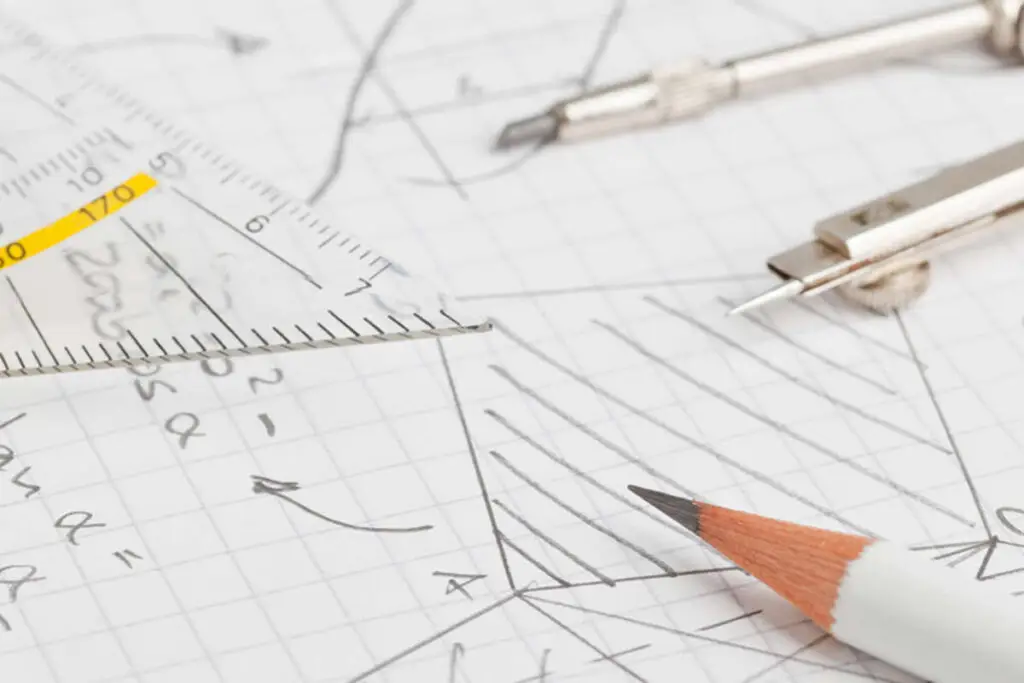 A pencil and compass showing maths working out on paper