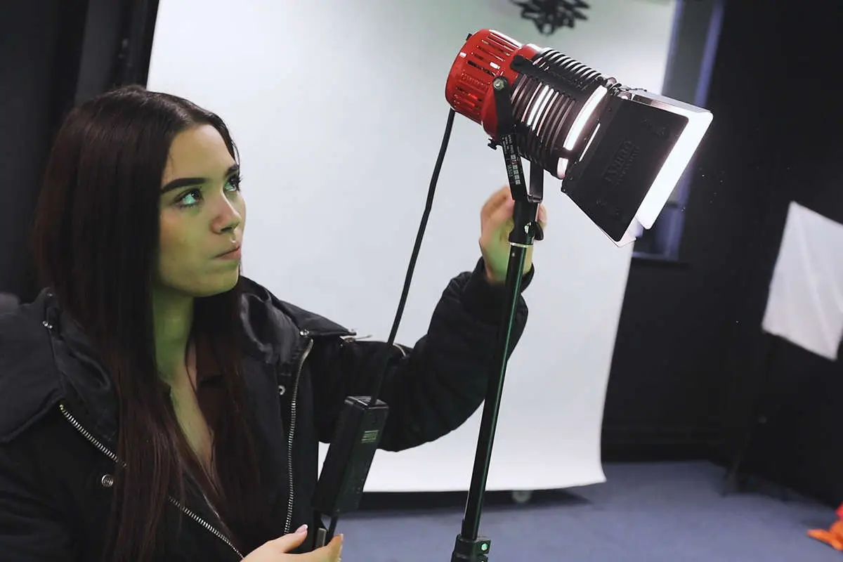 a media student adjusting the lighting of large lamp