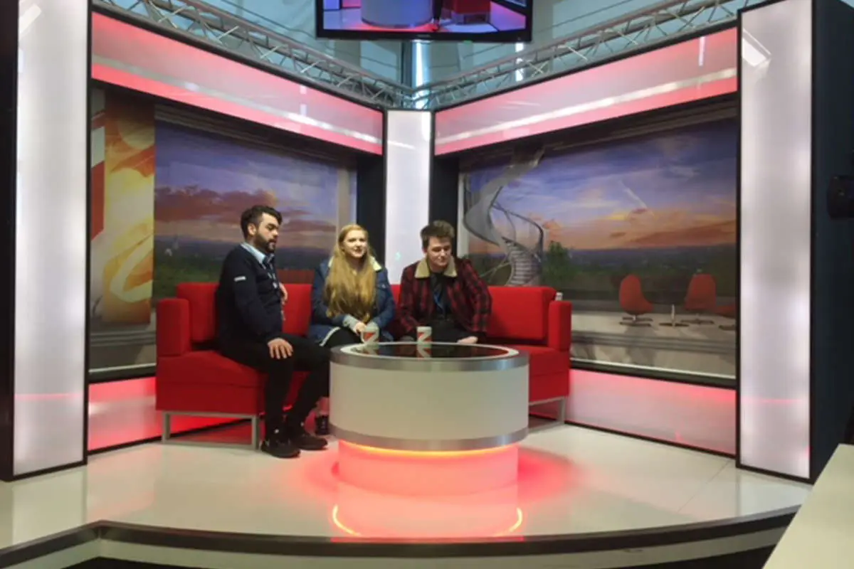 3 people sitting on a red sofa in the BBC news set