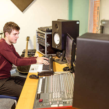 Male student in the studio playing the keyboard
