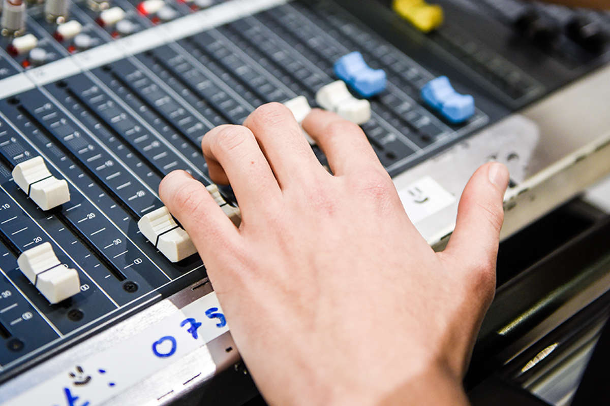 A hand on a sound mixing desk