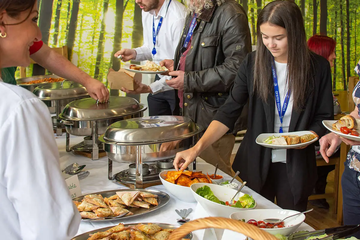 a young woman helping herself to some food from a buffet table