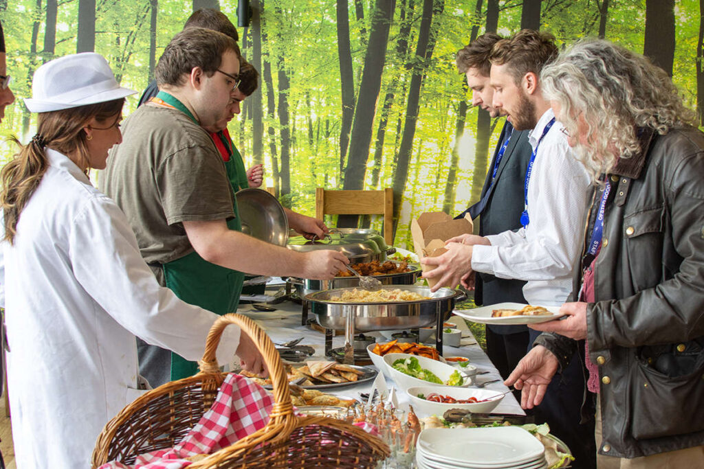 a line of people being served up food from the buffet