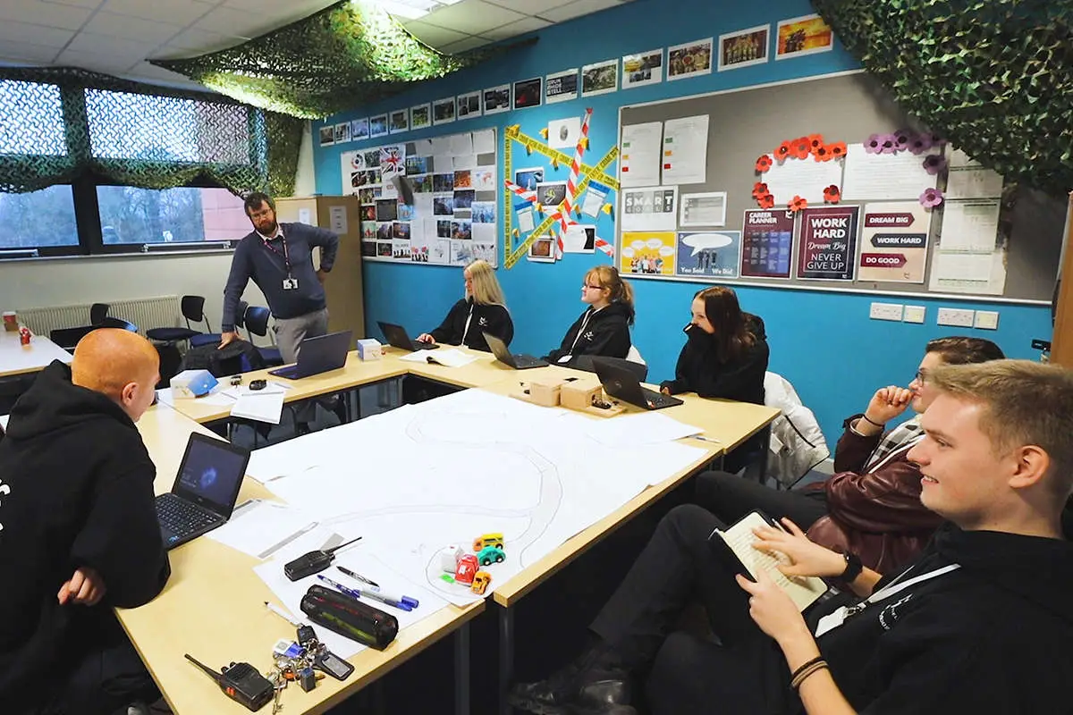 A group of students sat at their desk listening to a tutor