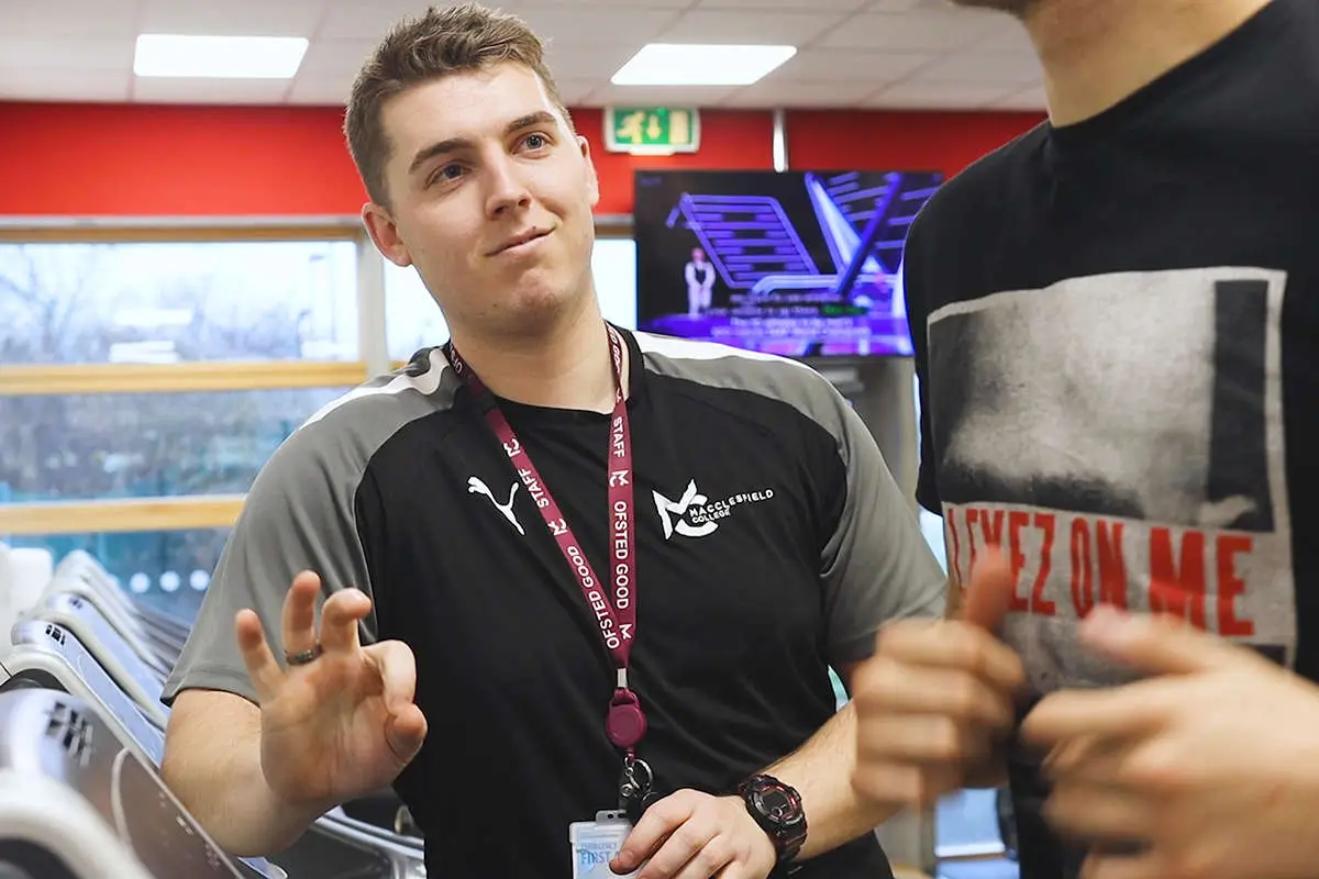 a sport tutor giving the ok sign with his hands to someone running on a treadmill