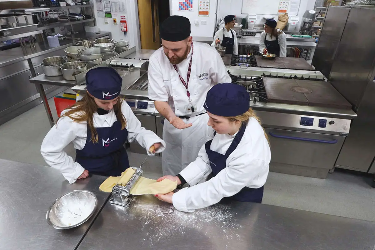 2 student practice making pasta together while the tutor observes