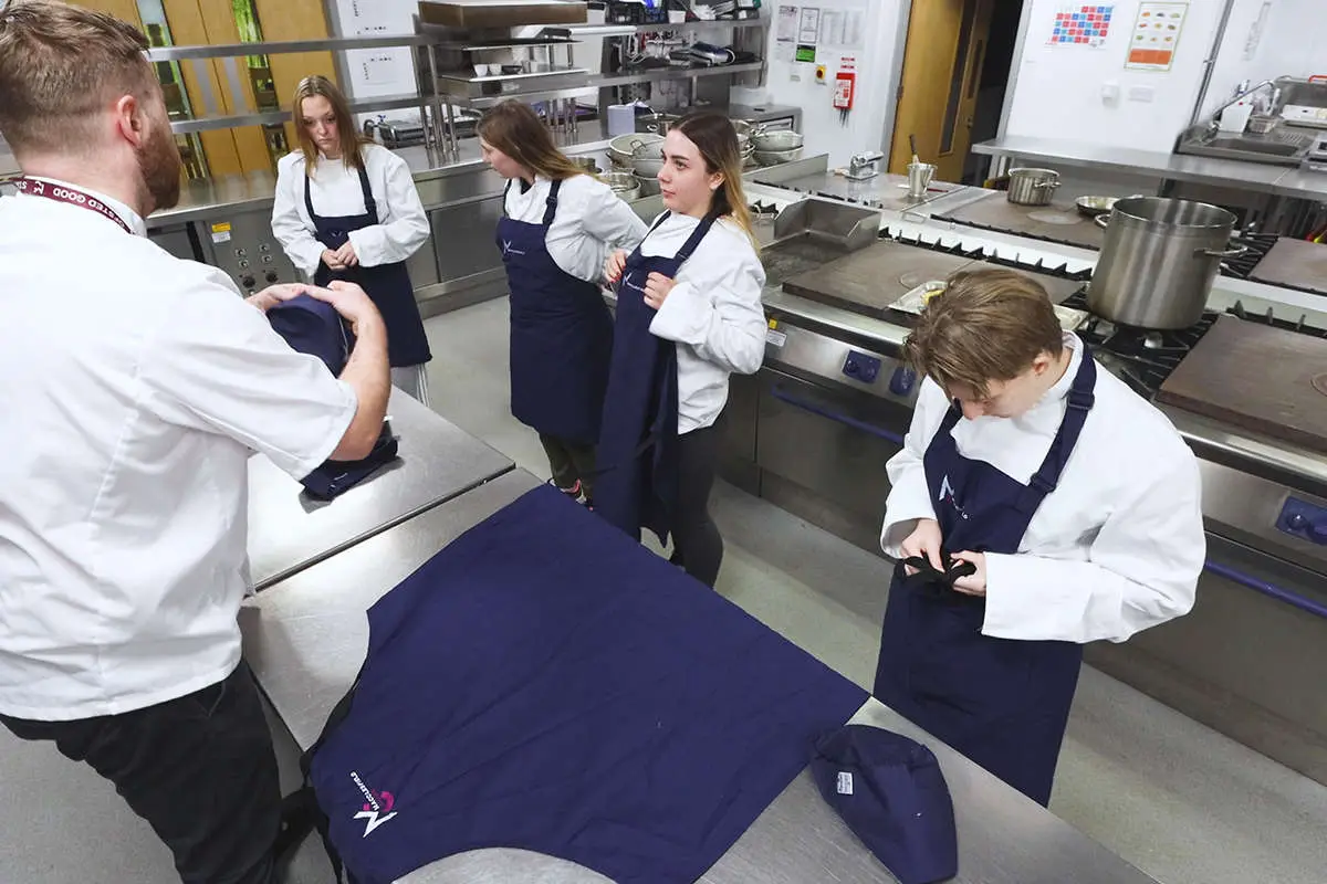 A group of chef students putting on their chef uniforms