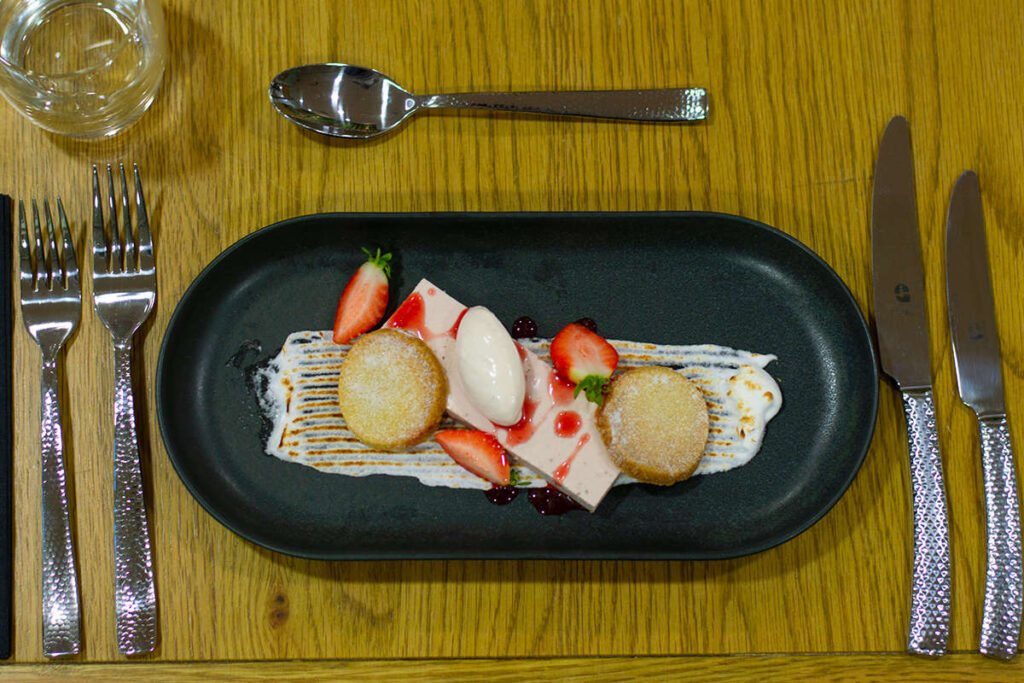 a table setting with a plate of fancily displayed shortbread biscuits, strawberries and ice cream