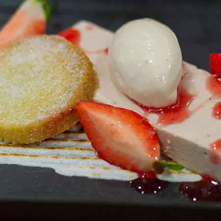 A close up of a plated short bread biscuit, strawberries and ice cream