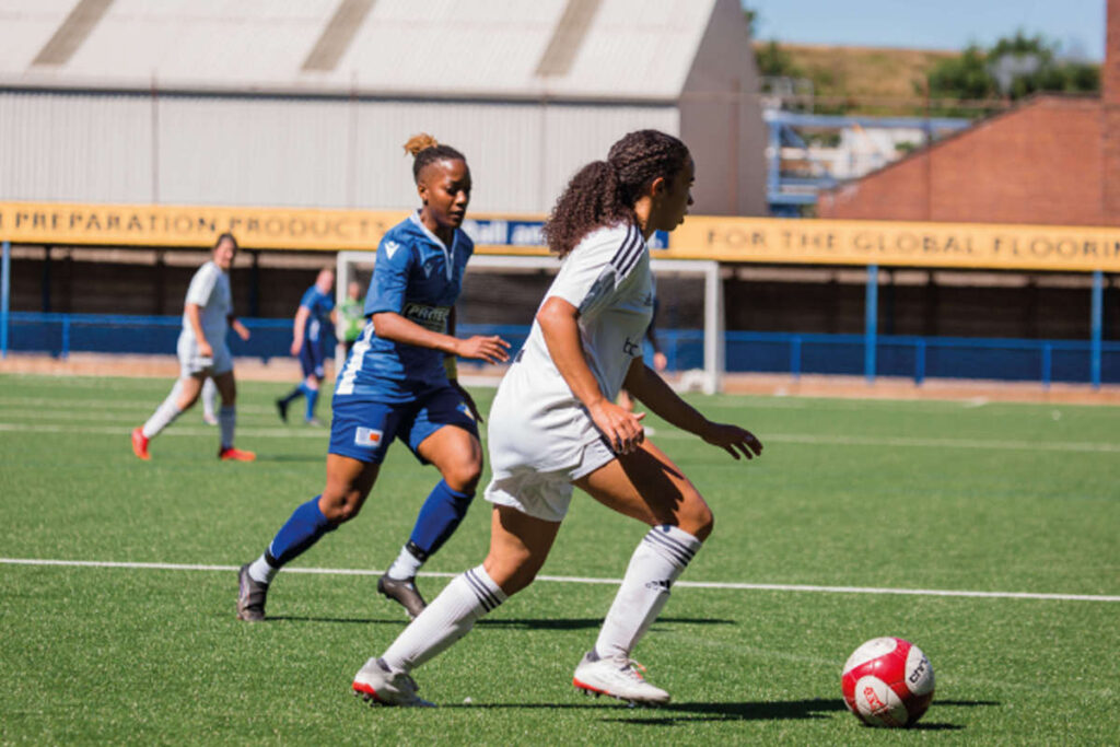 2 women's football teams having a match on an outdoor pitch
