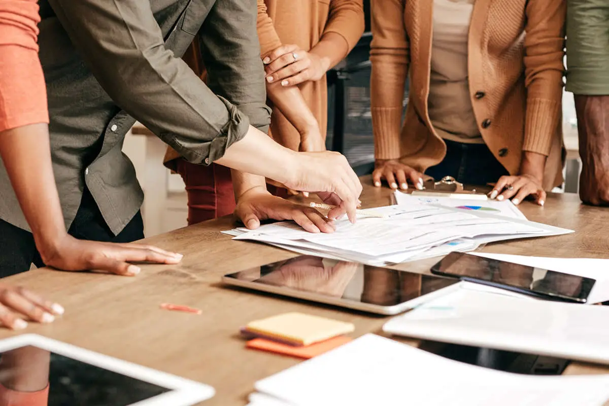 A group of young professionals gathered around a research paper and pointing