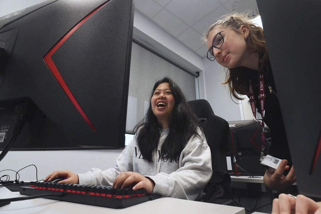 two student sat laughing at a computer