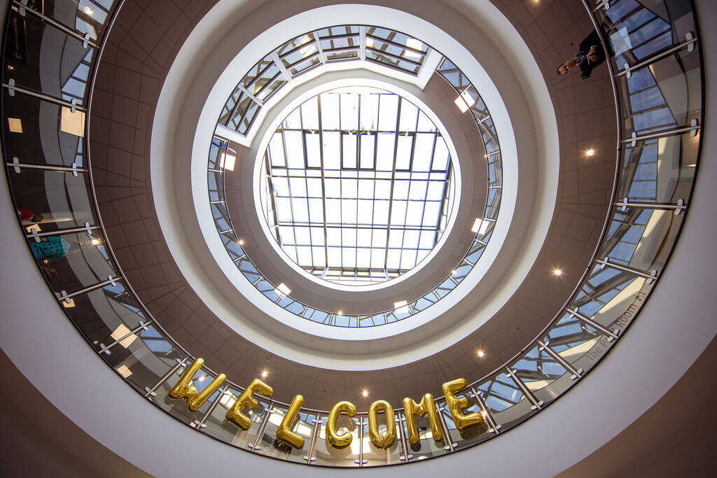 An upward view of the college atrium with inflated balloons spelling 'welcome'