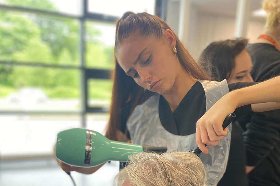 A hair and beauty student blow drying a client hair