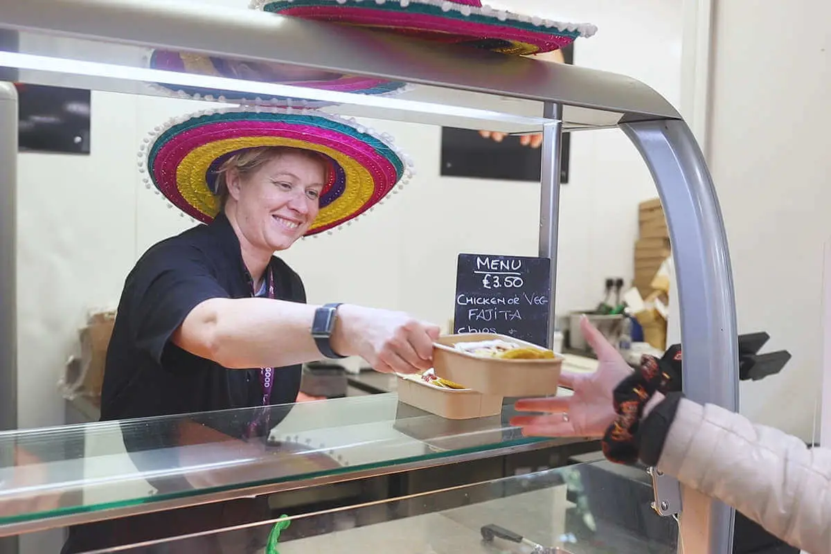 A woman serving in the canteen, wearing a sombrerro