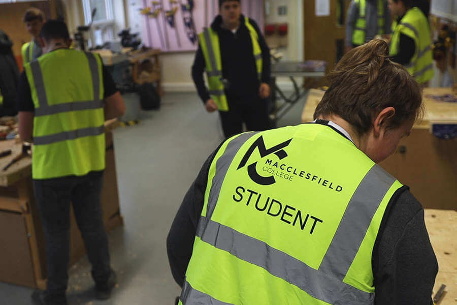 Macclesfield College Students in hi vis vest, busy in a workshop