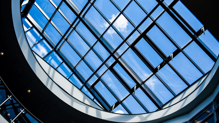 Looking through a large skylight on a beautiful day, a single cloud drifts past
