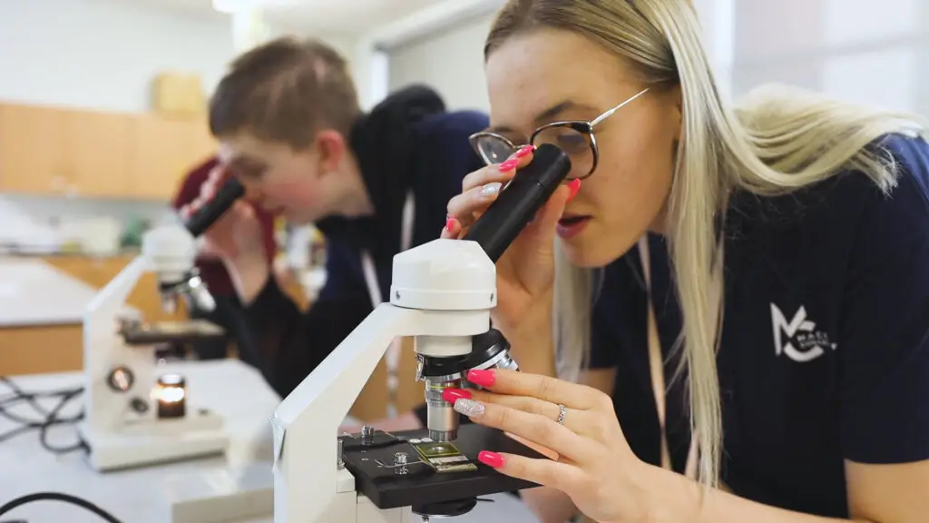 Two science students looking through a science equiptment