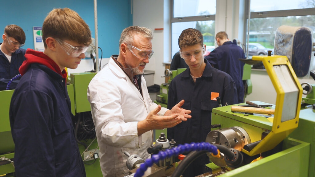Engineering Apprentices discussing machinery with their tutor assesor in the workshop
