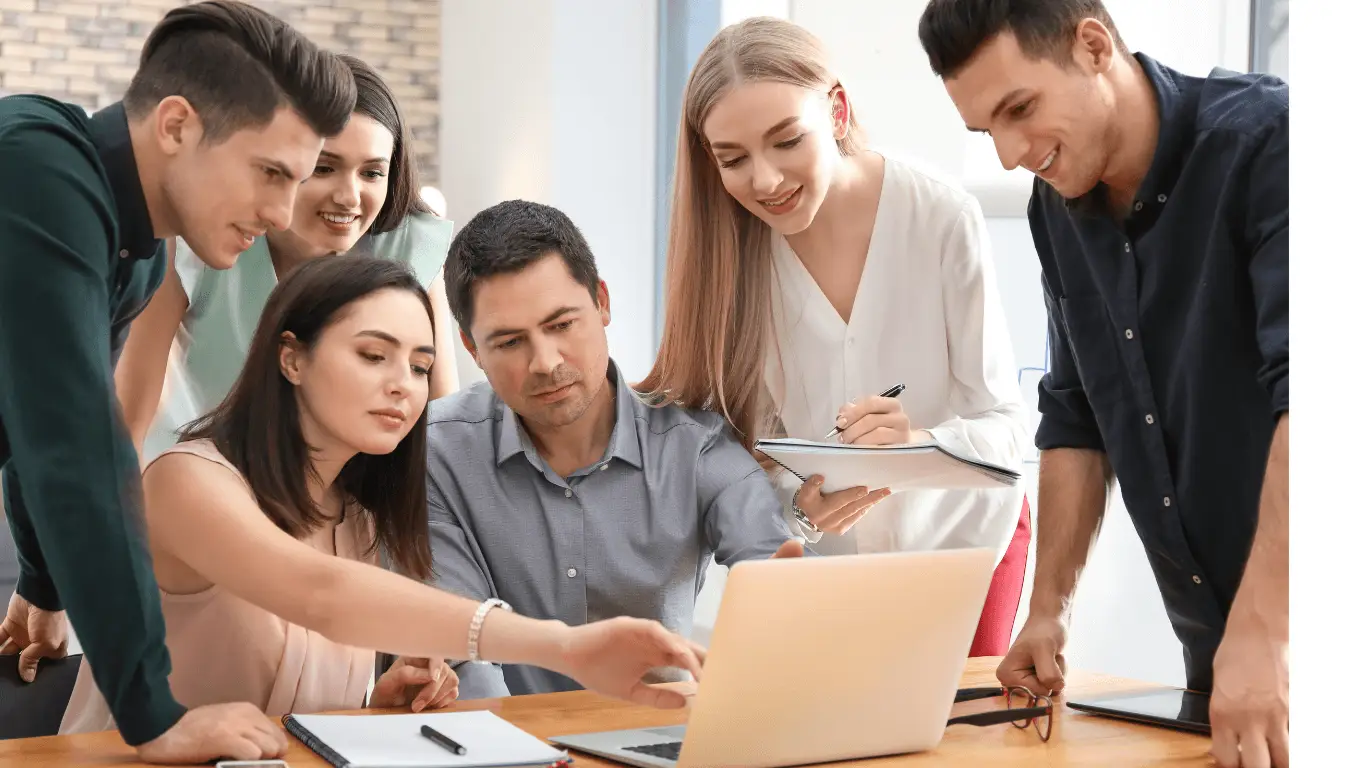 Business management apprentices looking at a computer and discussing work