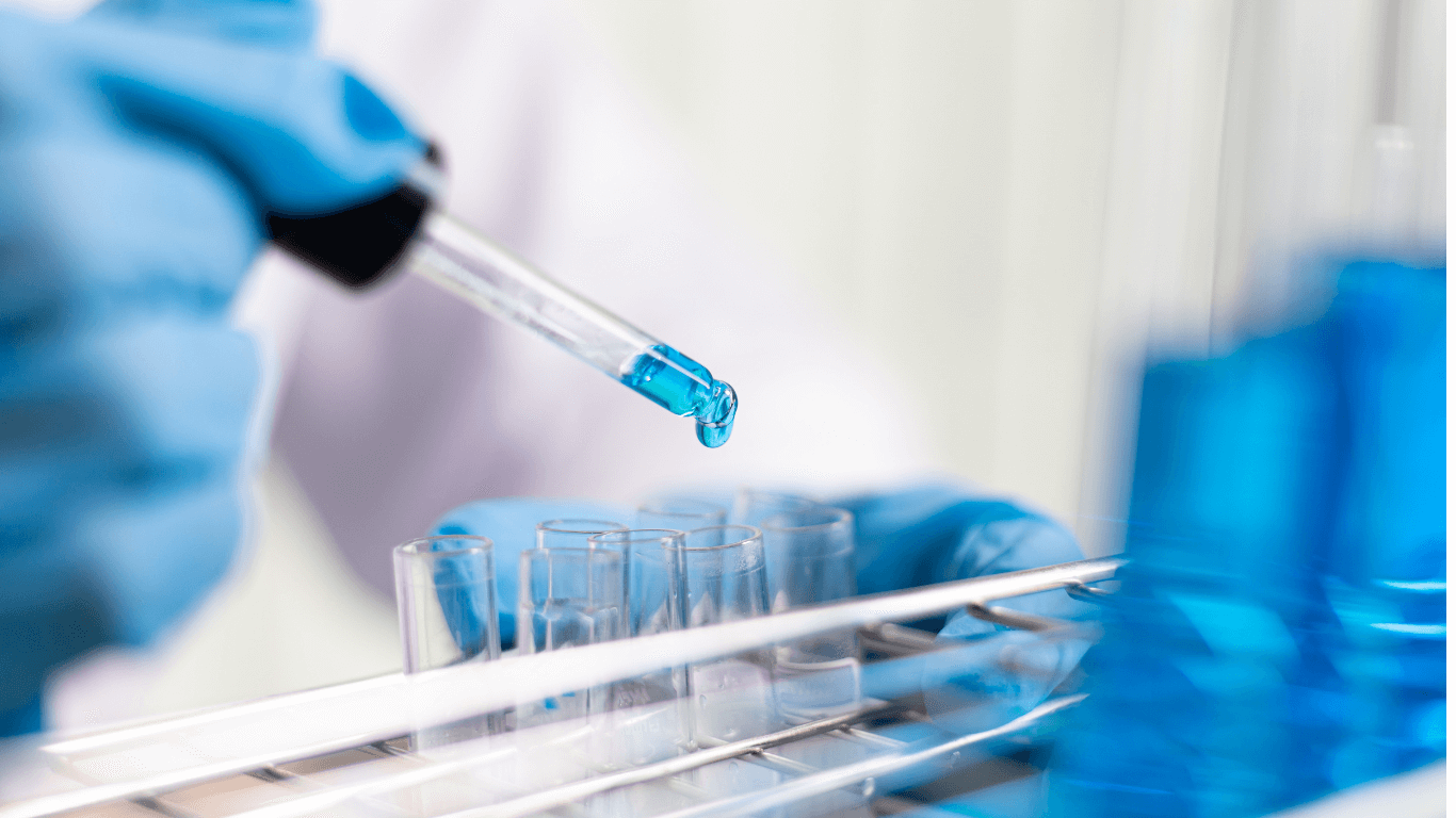 A scientist dropping a blue liquid into a test tube