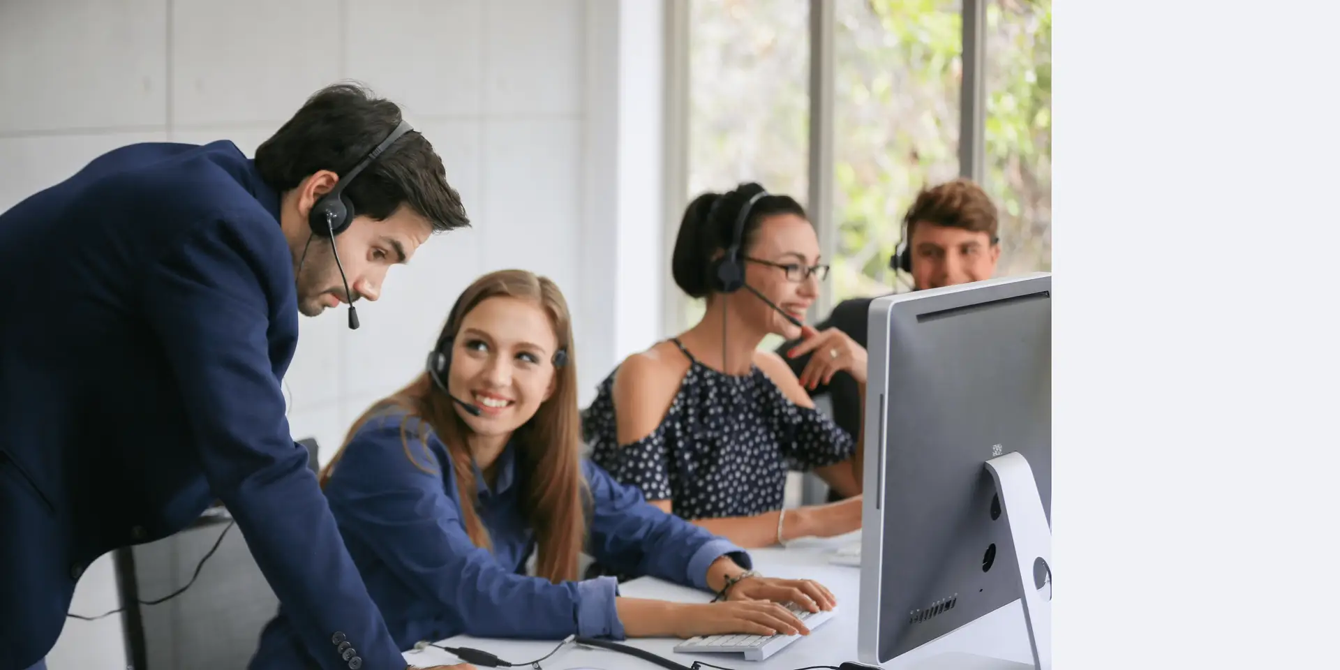 two customer services colleges chatting whilst wearing head sets in a office