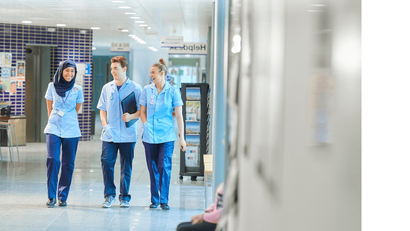 a group of health care students chatting while walking down a hospital coriddoor