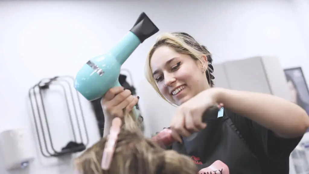 A hairdressing student is blow drying a client's hair