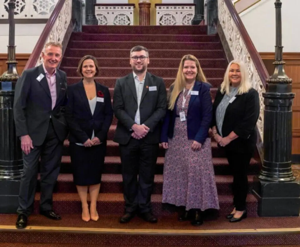 A group of people, dressed in business attire, are smiling for a photo