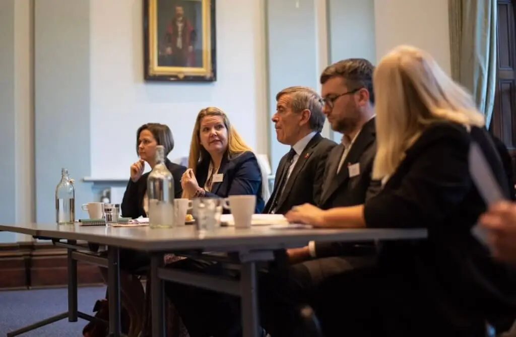 A group of people, dressed in business attire, are sitting at a table.