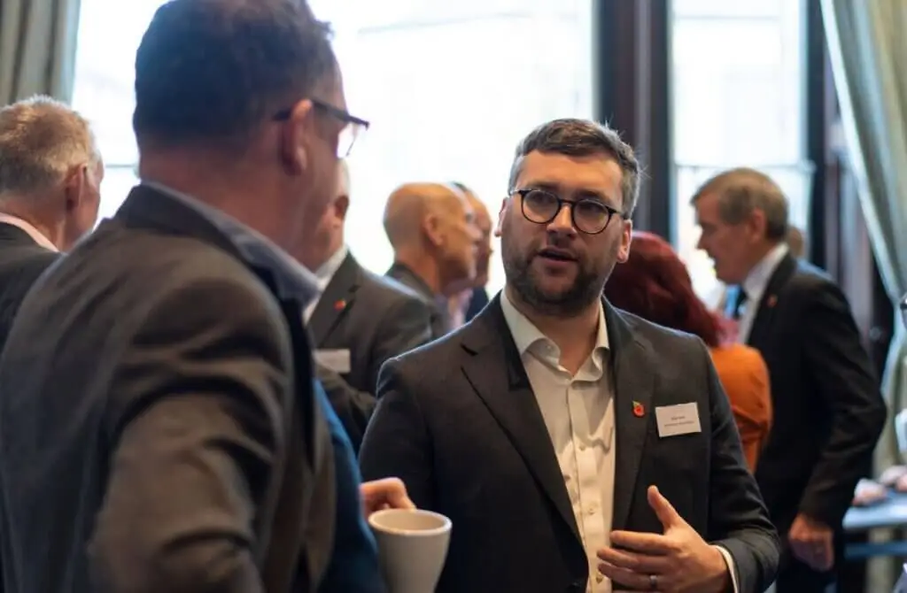 Two men, dressed in business attire, are at a breakfast event