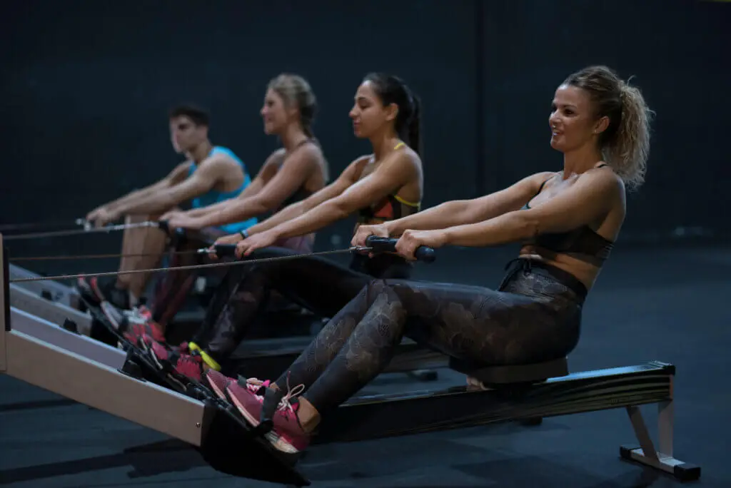 A group of people are using rowing exercise equipment