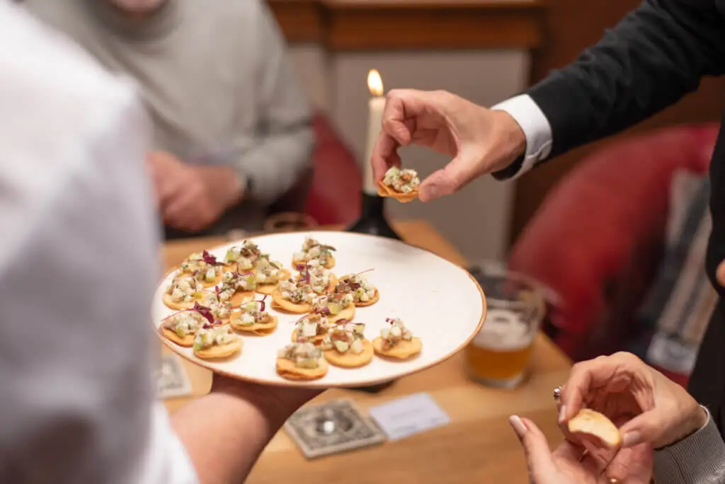 A whites chef academy student is serving food to a group of people during an event