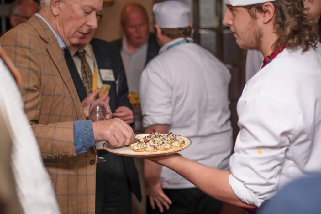 A whites chef academy student is serving food to a group of people during an event
