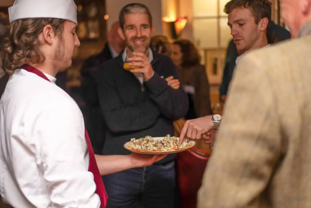 A whites chef academy student is serving food to a group of people during an event