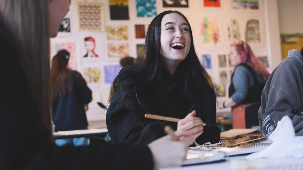 An Art student smiling whilst she is working.