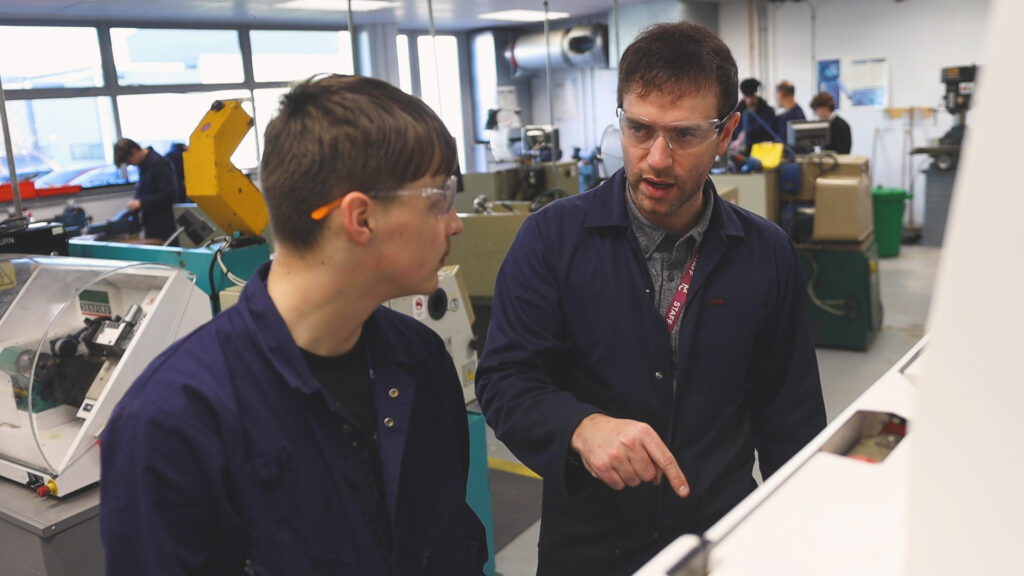 An Engineering student is listening to an Engineering teacher talk about machinery.