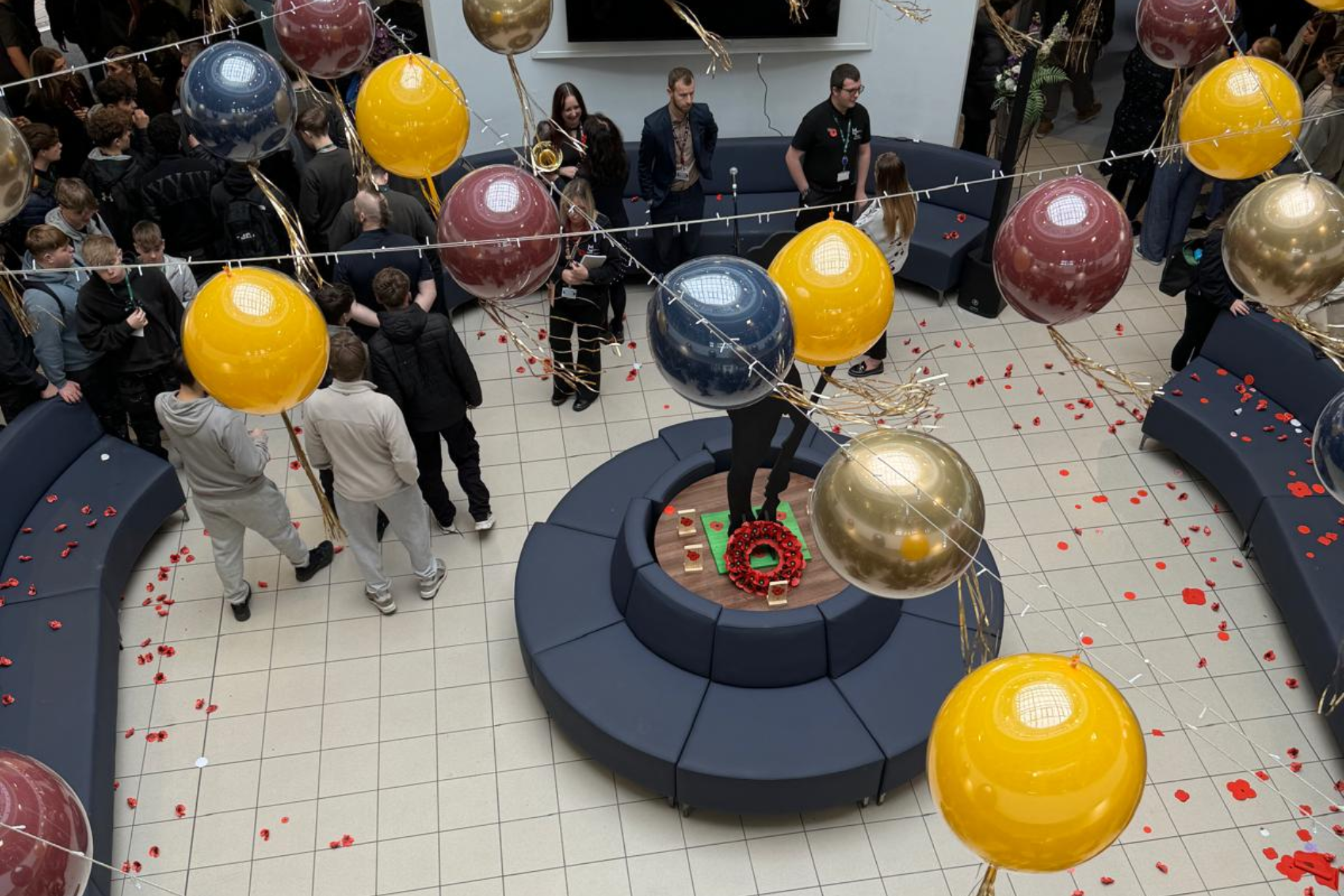 A photo of the Rotunda during the Remembrance Service, with staff and students standing around the memorial display.